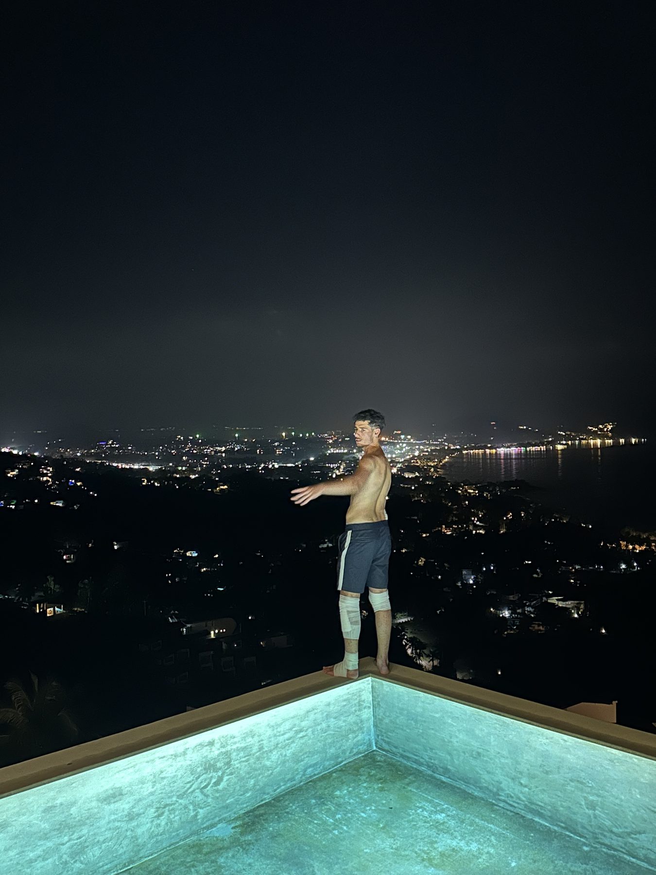 Nabil aan de rand van een infinity pool, boven de lichten van de stad